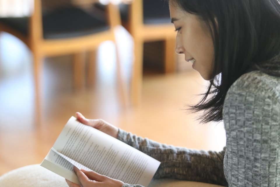 Young woman in a sweater smiling and reading the Immerse Bible