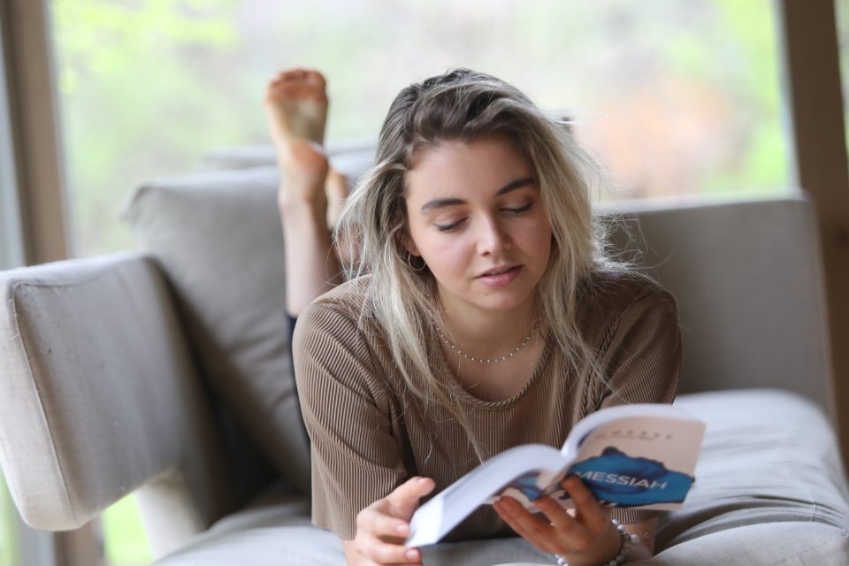 Young woman laying on her stomach reading Immerse: Messiah