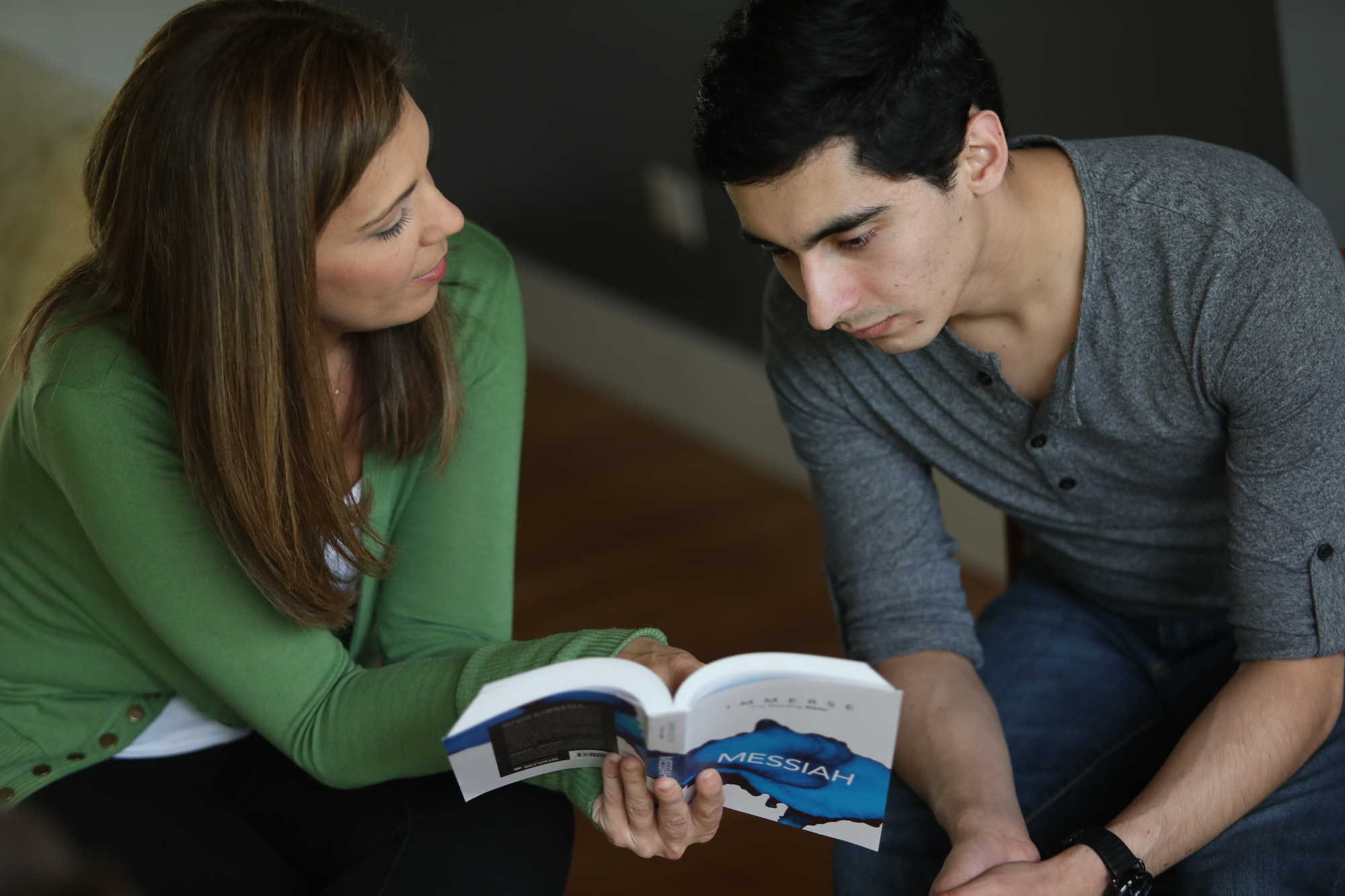 A woman holding Immerse: Messiah and having a discussion with a young man