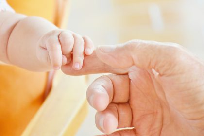 baby hand holding adult finger