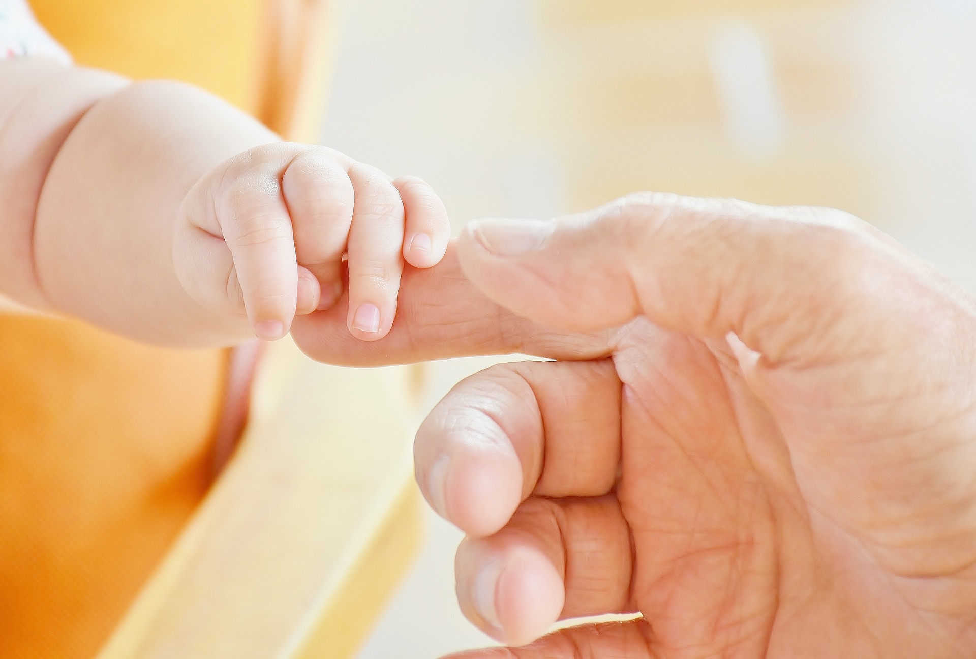 baby hand holding adult finger