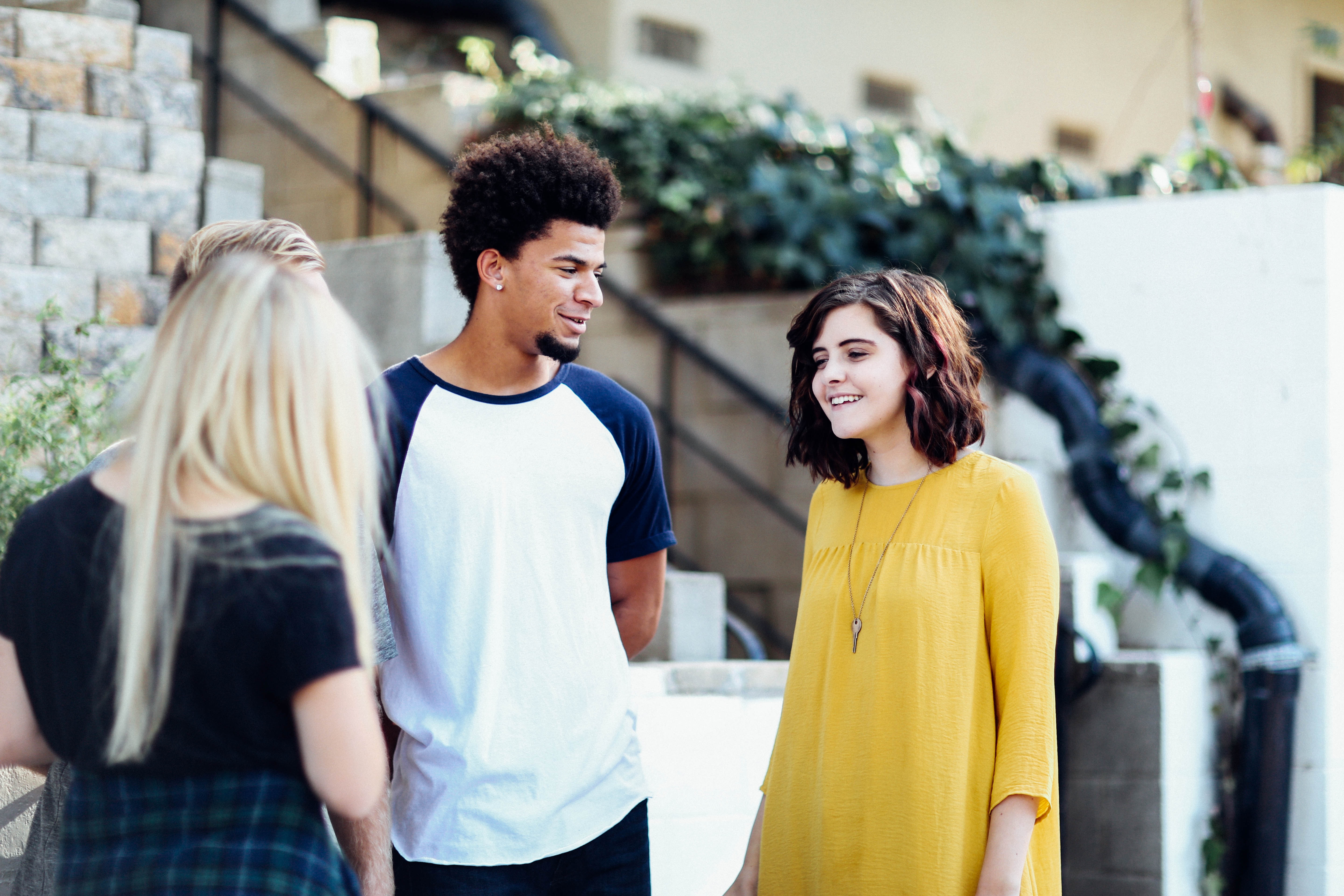 Group of young people happily talking while standing in an open interior