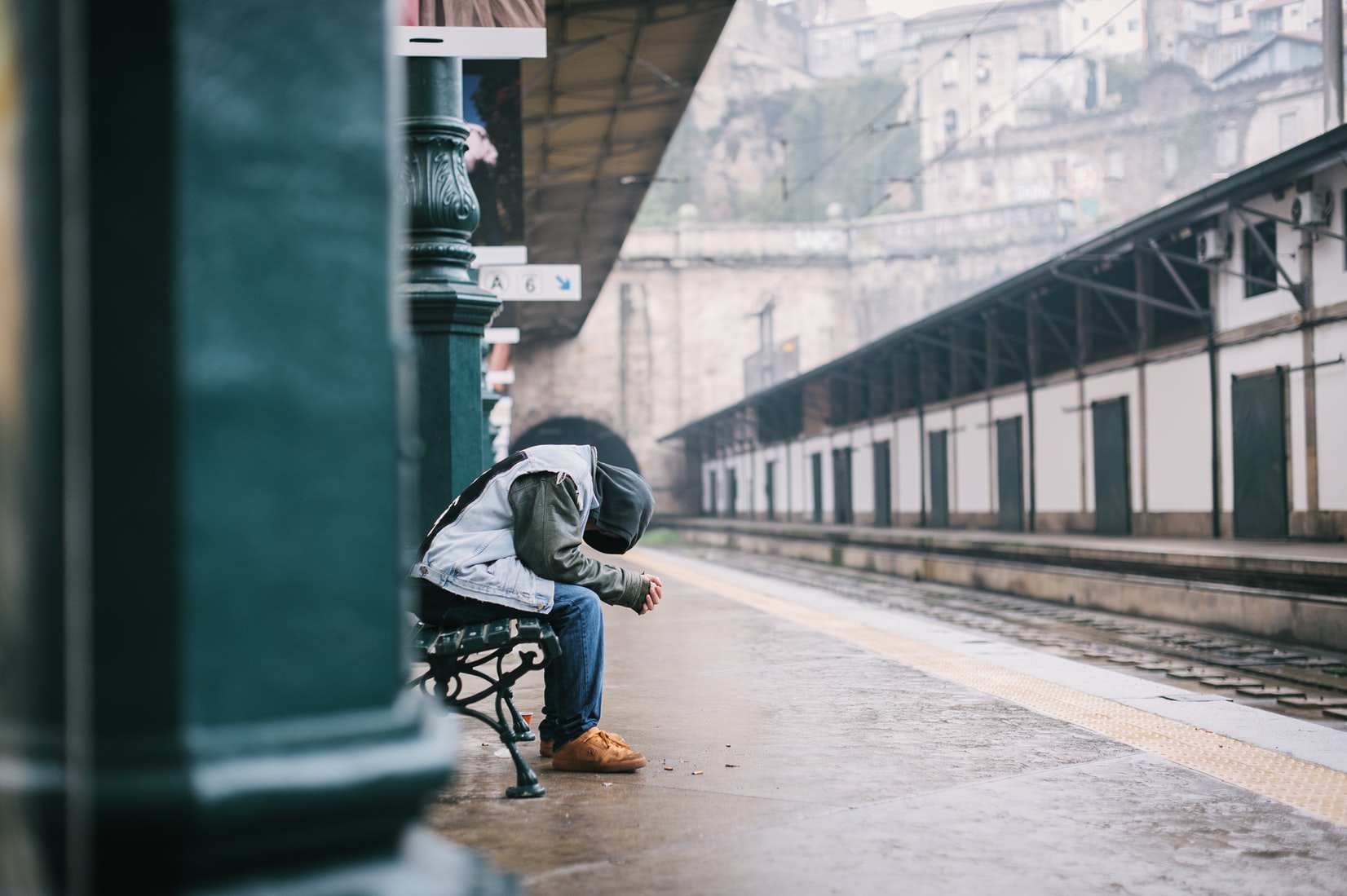 man sitting on bench with head down