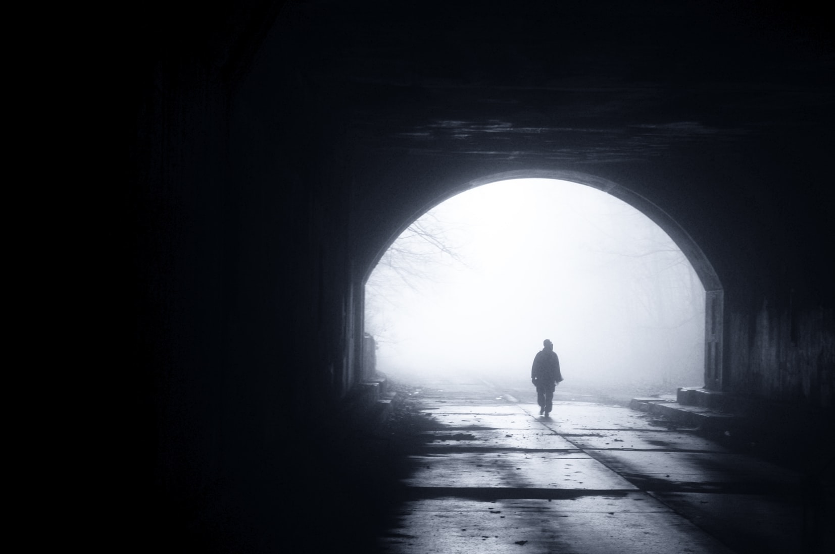 person walking under bridge in gloomy dark weather
