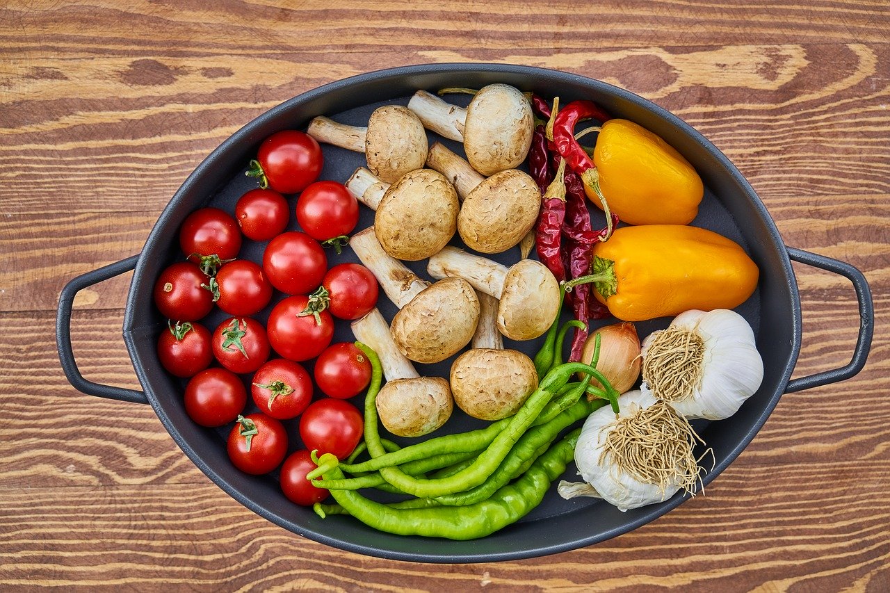 Black oblong skillet with fresh vegetables on wooden countertop
