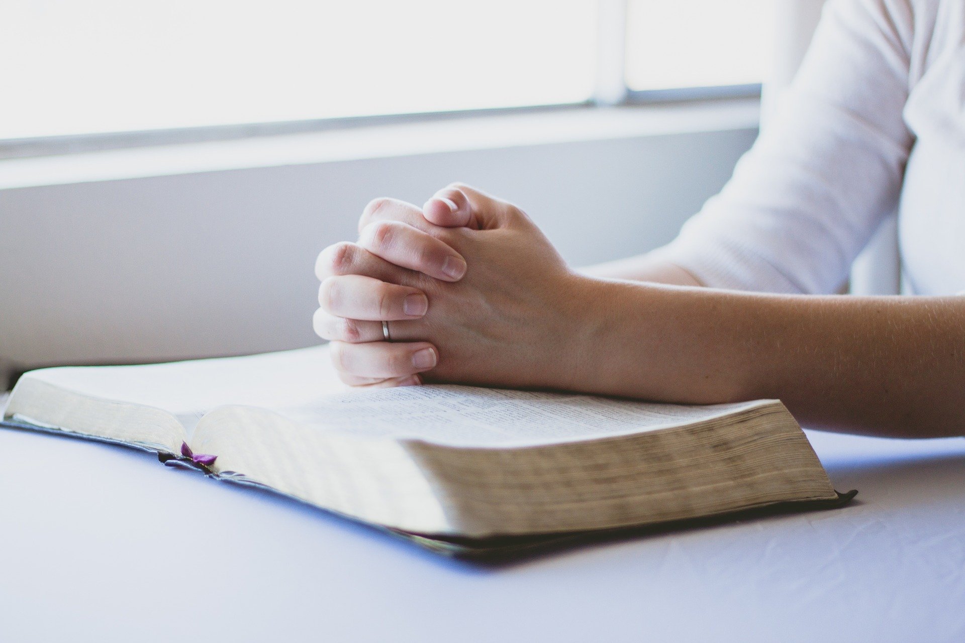 person praying with hands folded in room