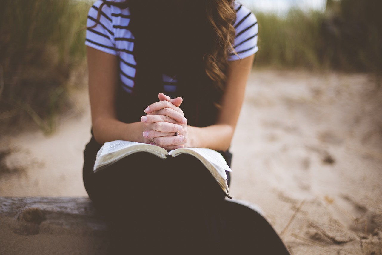 woman sitting and praying at beach