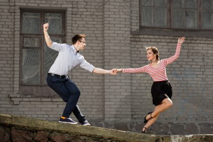 happy young couple swing dancing outside building
