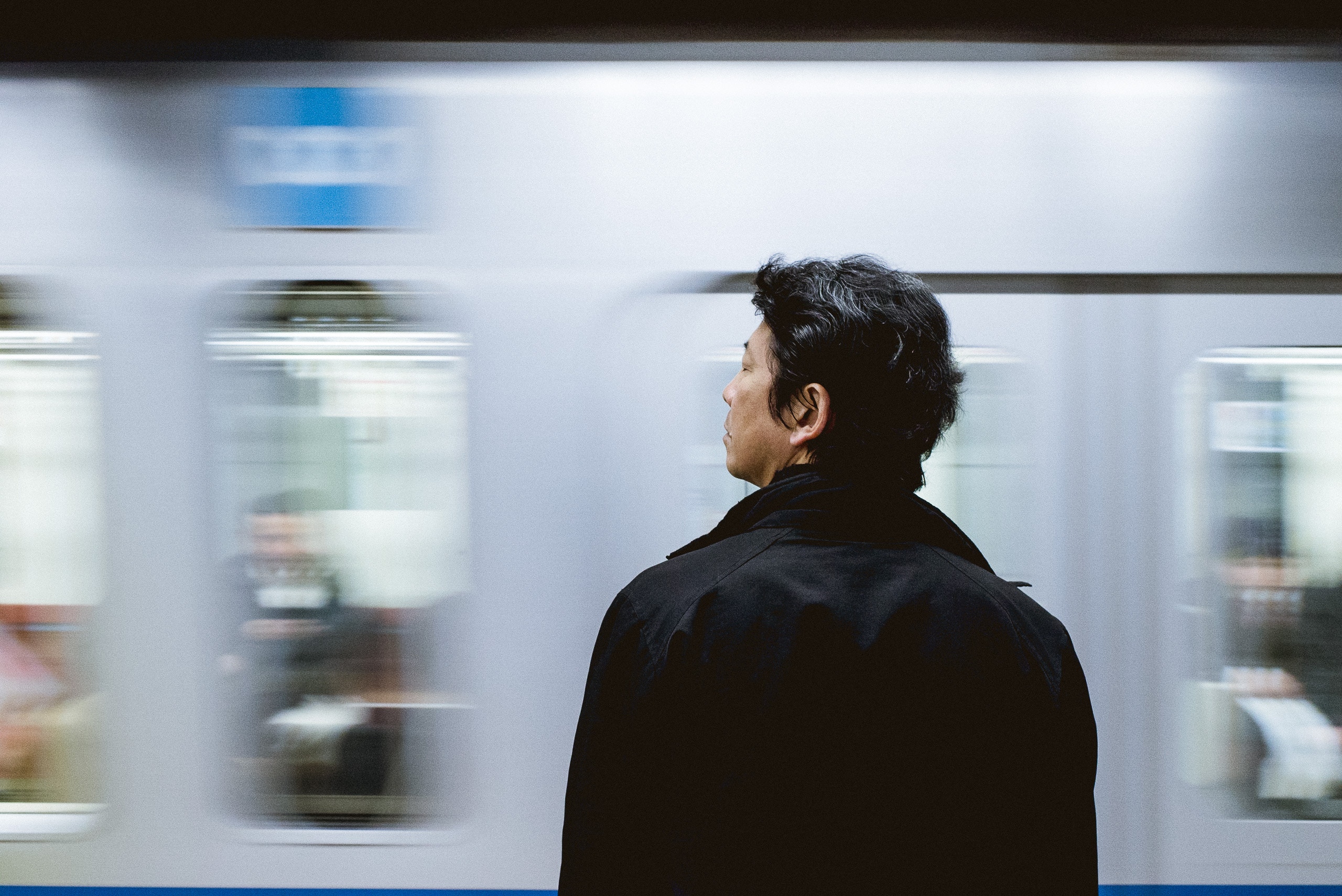 Image of a lone male standing by a fast moving train.