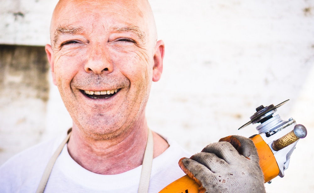 A happy man holds a buzz saw in close up. He is using his spiritual gifts by performing construction jobs, either around his church, or in ministry.