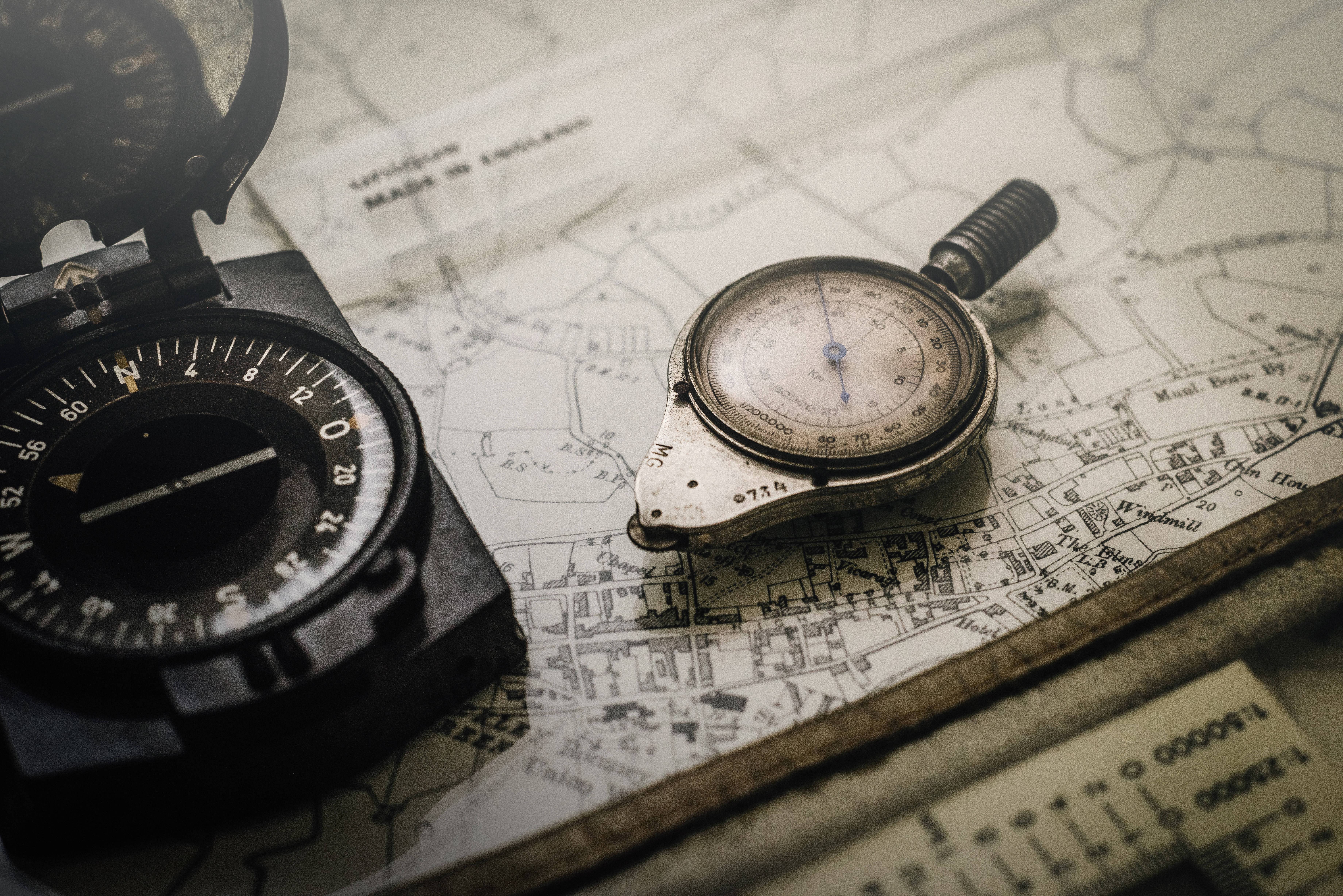 A compass and stop watch sit atop a map. Have you wondered, does God exist?