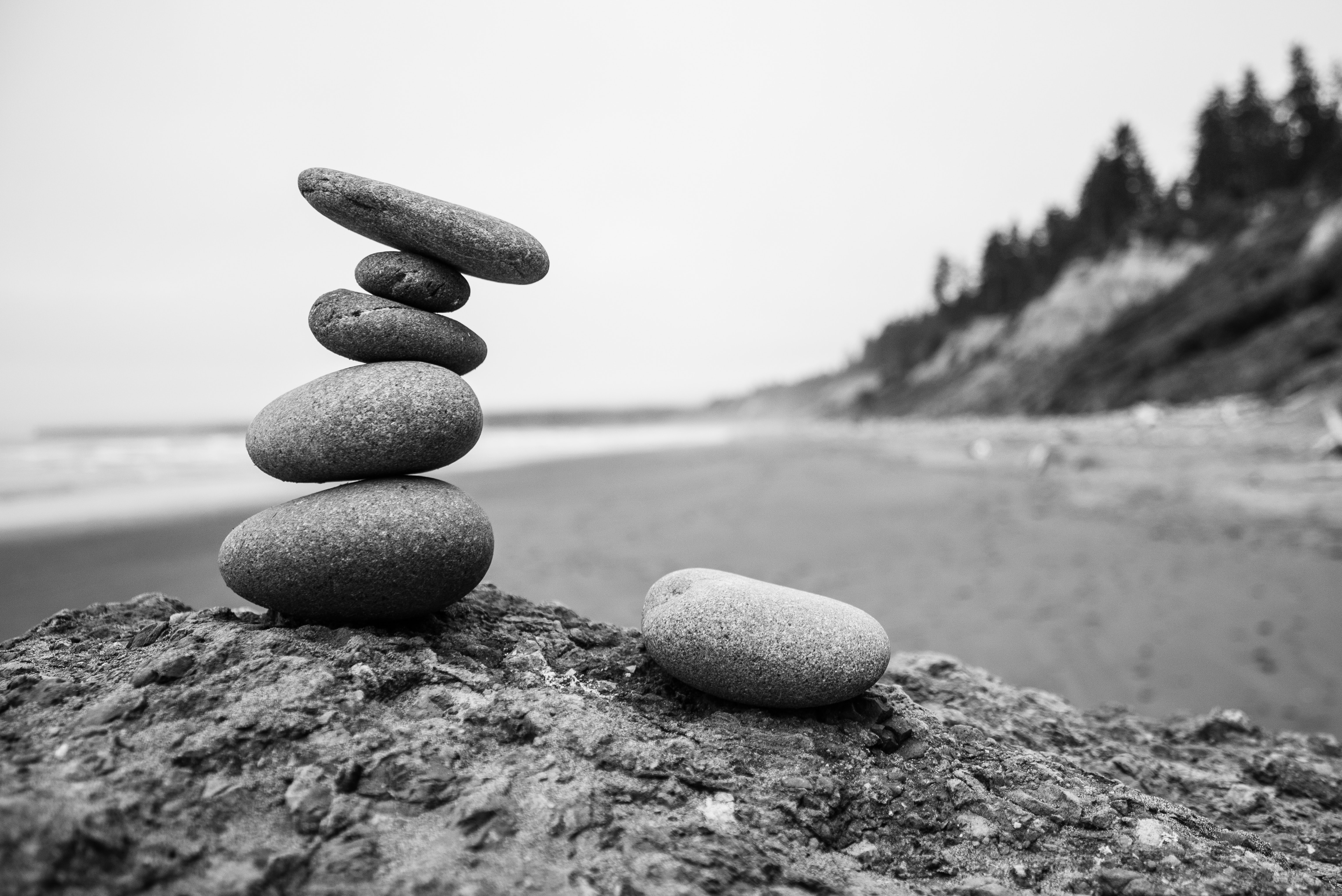 A pile of smooth stones stand on a sandy beach in a black and white photograph. God gave us the Proverbs to teach us and provide us with wisdom for life.