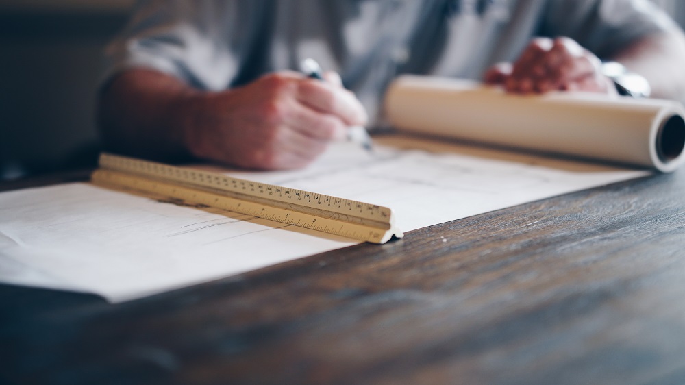 A pair of hands, seen in close up, work on a technical drawing with a plastic ruler beside them. Your God-given spiritual gifts may take on many uses and forms.