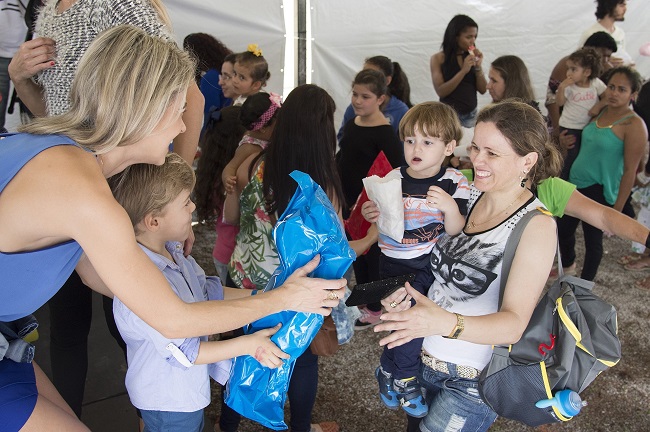 A woman and her child hand another woman and her child a package. They are all smiling and surrounded by other people waiting in lines. We can use our spiritual gifts in many different ways, such as organizing charity drives.