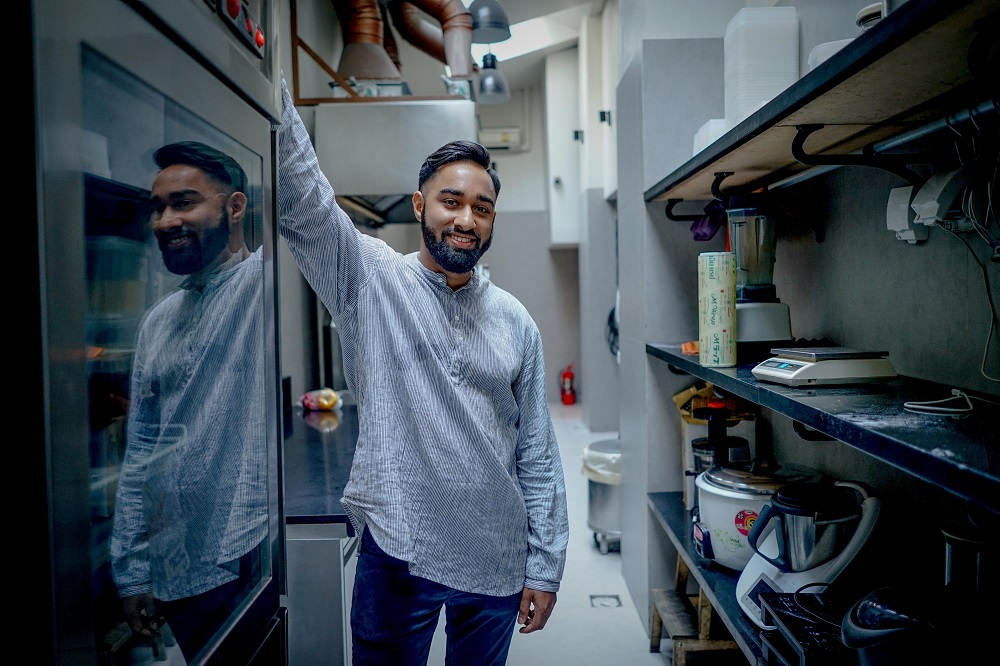 A man stands in a professional kitchen with a smile on his face. He is using his spiritual gifts to move the Kingdom and it brings him great joy!