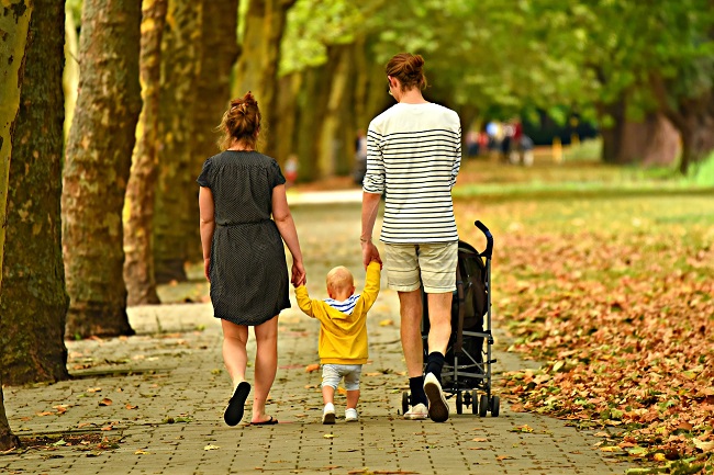 Parents walk with their small child on a path surrounded by trees and grass. Sometimes we use our spiritual gifts to serve those closest to us.,