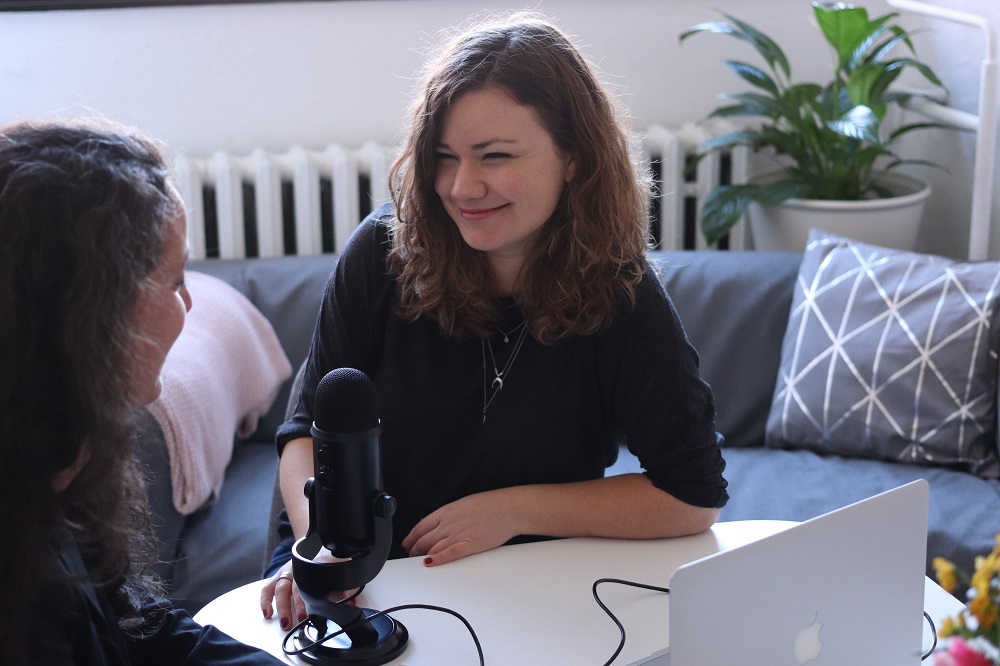 Two women smile at each other as they sit at a table recording a podcast. You can use your spiritual gifting in many different ways to help move the Kingdom!