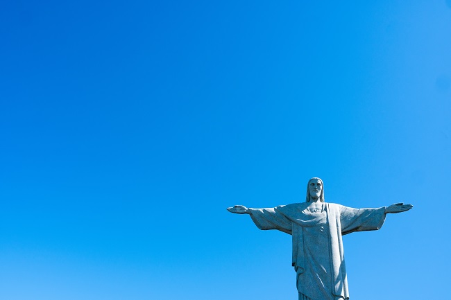 The statue of Christ the Redeemer is photographed from below, with a brilliant blue sky behind it. In order to abide in Christ, we should live by His Word.