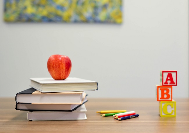 A teacher's desk is adorned with a pile of books, pencils an apple and ABC blocks. It's important for Christians to continue learning throughout life so that we might remain close to Jesus.