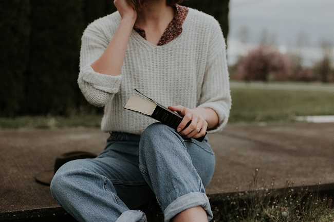 A woman sits on a curb with her Bible in her lap. Daily study of your Bible really helps with understanding the heart of God and why we should strove to be more like Jesus.