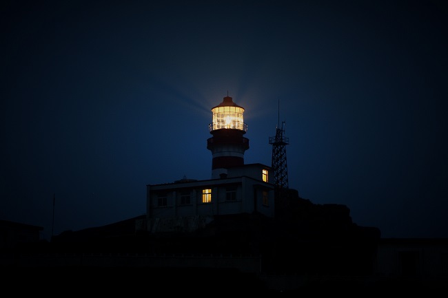 A lighthouse shines its beam of light through a dark sky. Jesus came to earth as our beacon of light!