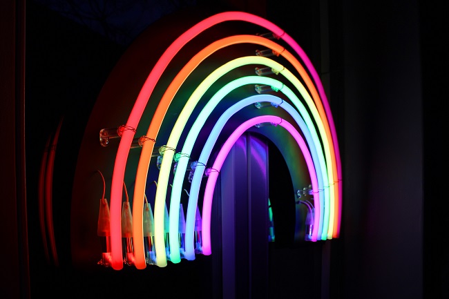 A neon rainbow lights up a dark wall. 