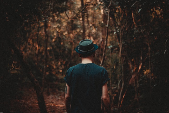 A young man, seen from behind, walks through a dimly lit but pretty wood. Jesus came to rescue all of us, especially those extremely lost.