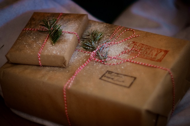 A couple of beautifully wrapped gifts with red and white string and sparkly faux snow sit waiting to be opened. Jesus is God's greatest gift to the world and send Him to be our savior when we needed a new hope.