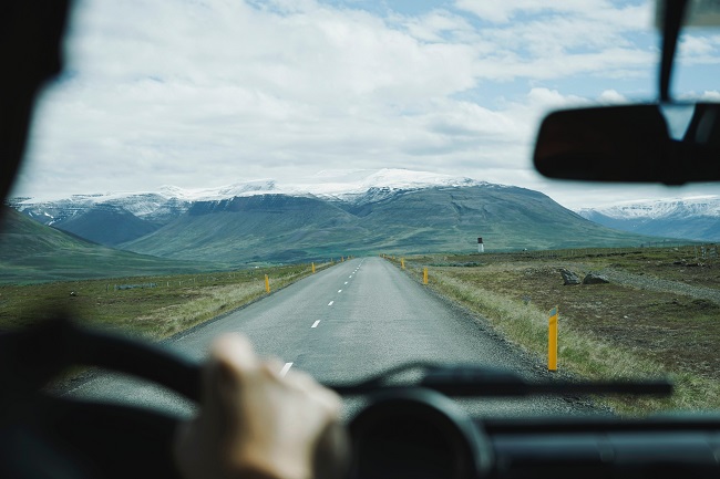 Looking out at a straight, long road in a landscape view through someone's car windshield. God can make your journey more fulfilling if you surrender the wheel to Him.