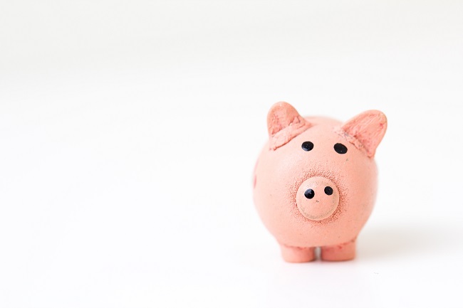 A pink piggy bank sit on a white background. Does spending money on ourselves bring us true joy? Or can giving it away do that?