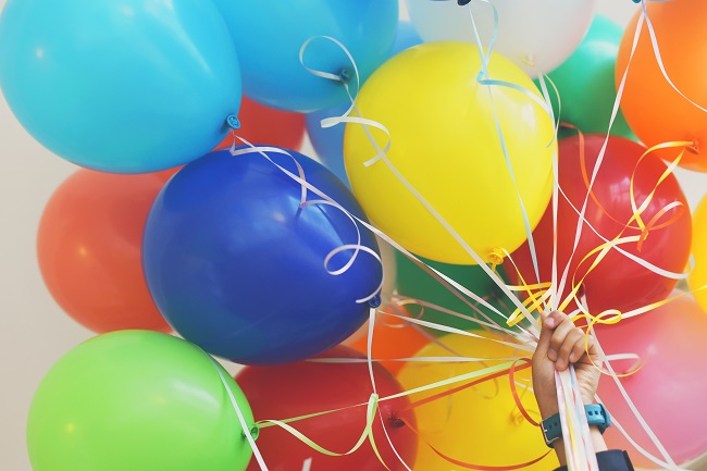 A big bunch of colorful balloons fills this photo. They are held together with equally colorful ribbon and we see a person's hand grasping that ribbon. Living the good life isn't about having a lot of money, once we realize money is God's possession, not ours.