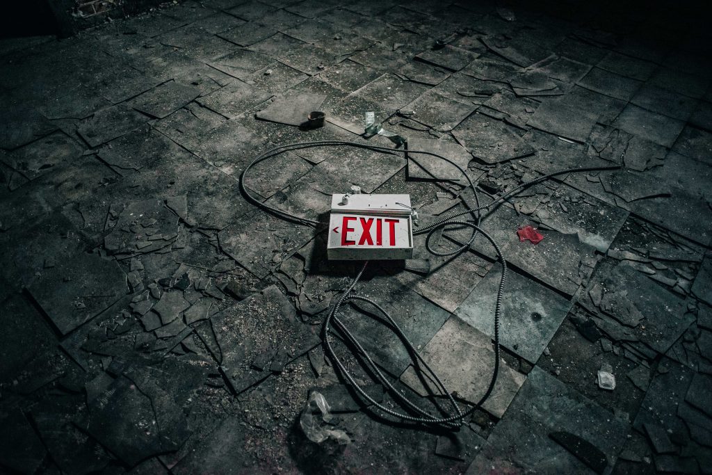 Image of a broken Exit sign on a floor, demonstrating God's love for us all