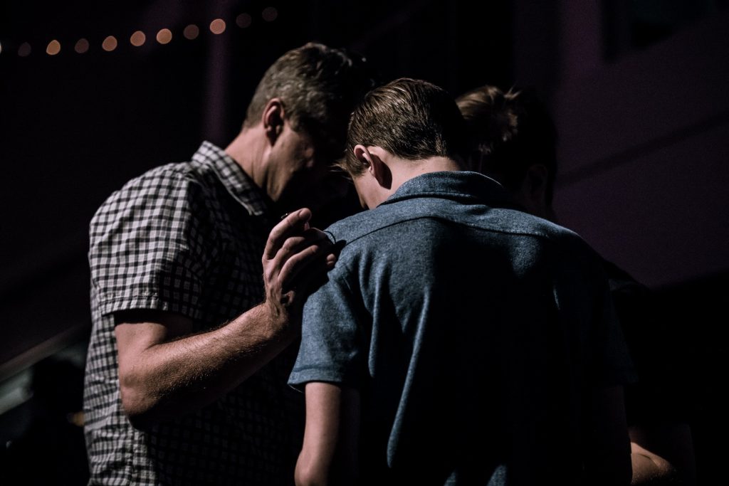 Image of a father praying with his son, demonstrating God's love for us all
