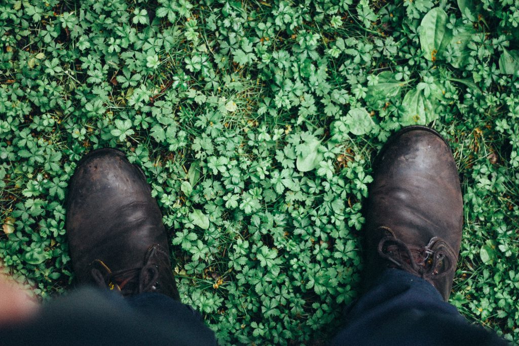 A man's boots stood on green grass, indicating he has come home to God's Love