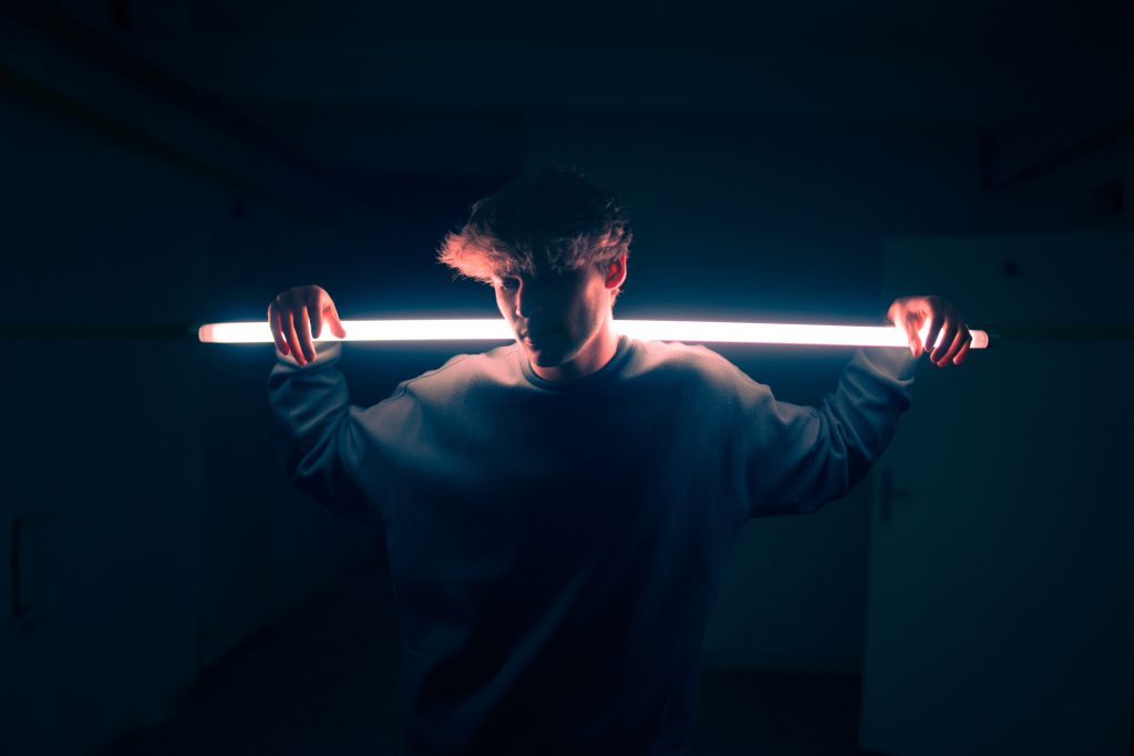 A young man holds a strip light on his shoulders, demonstrating God's love for us all, even in the dark