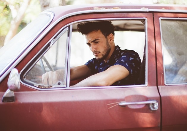 A young man in an old car wonders if he can pray to God for a new car.