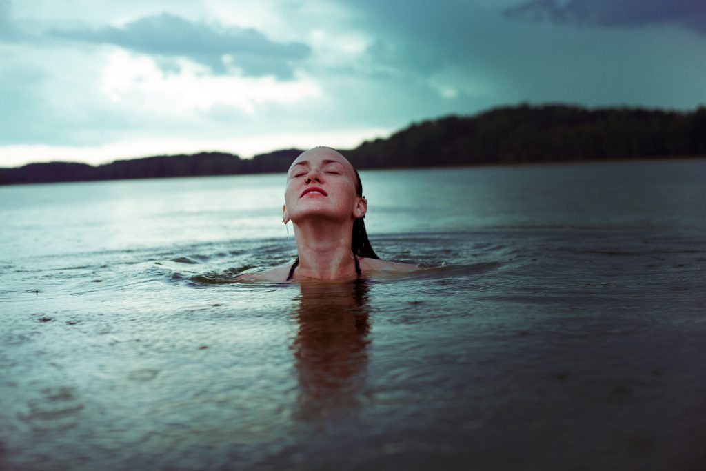 Young Woman emerges from baptism waters with a smile on her face. What is baptism? 