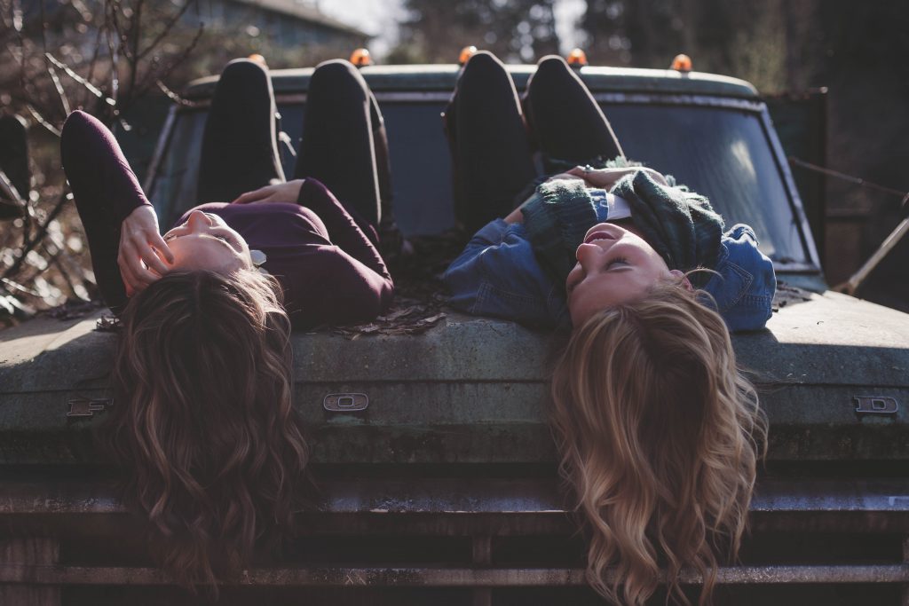 Two women chat about faith while hanging out on a truck hood.