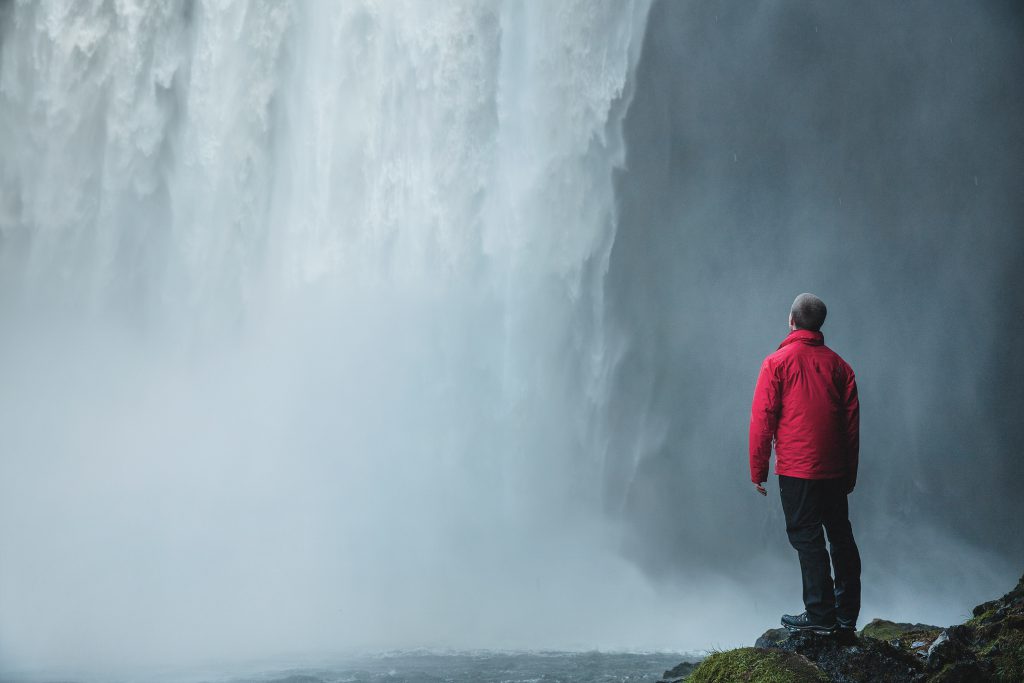 A man stands beside a waterfall. depicting the freedom found in recovery through Jesus. Devotionals for new believers.