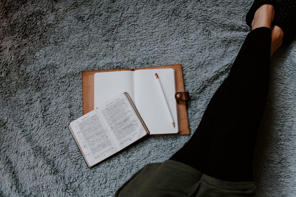 A woman reads her bible and writes a list in her journal, referencing how we should be making lists of grace, not resolutions, this new year.