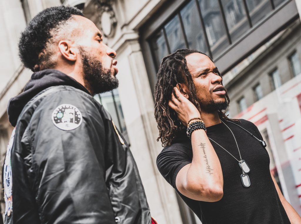 Two young men chat on the street about faith.