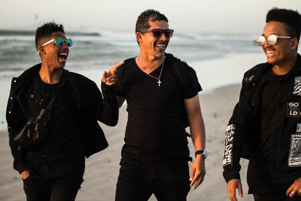 Three Male friends enjoy the beach, and the small group that they make.