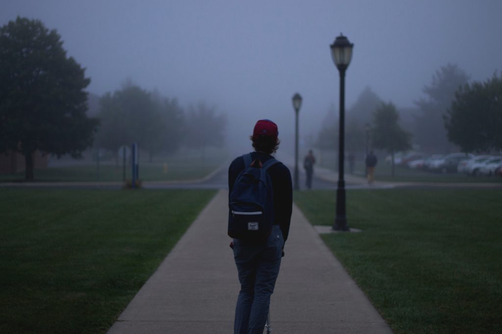 A male student stands in a gloomy, misty morning light. Share your testimony.