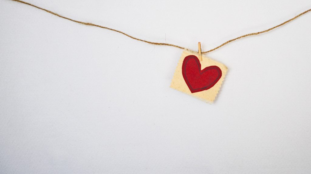 Paper heart pinned to a string across a white wall. Think about your testimony and how you would tell it to others.