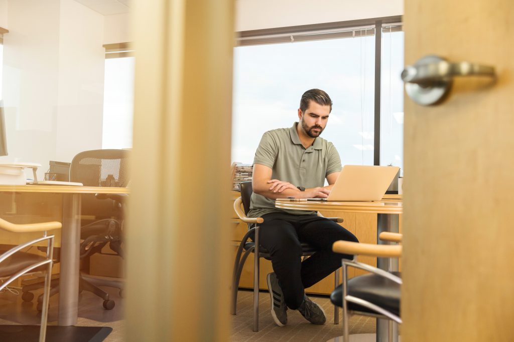 A salesman sits at his desk, on his computer. 