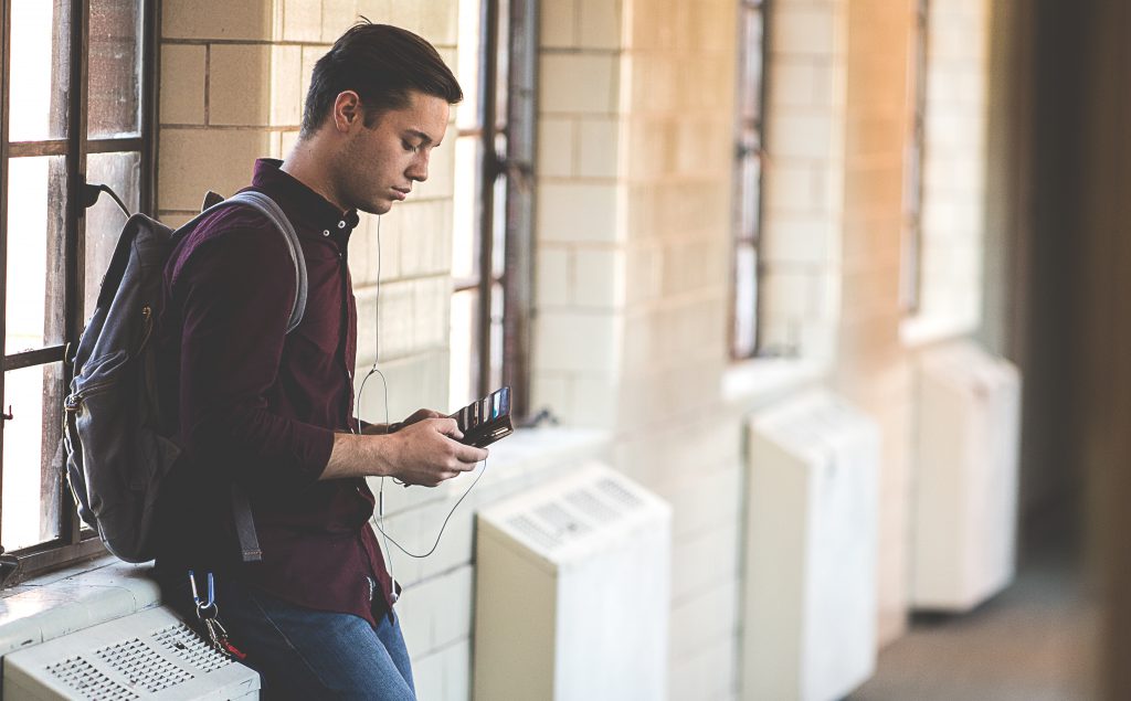 A student stands in a hallway listening to his phone. It's important to think about your own testimony.