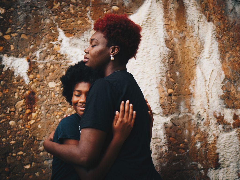 A mother and daughter hug closely and smile with their eyes closed. You can stop sinning with God's help.