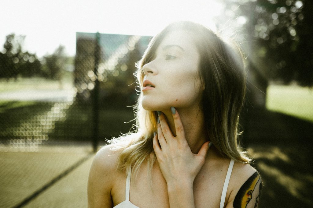 Young Woman in a park looks pensive as she touches her throat in low level lighting. How can I stop sinning?