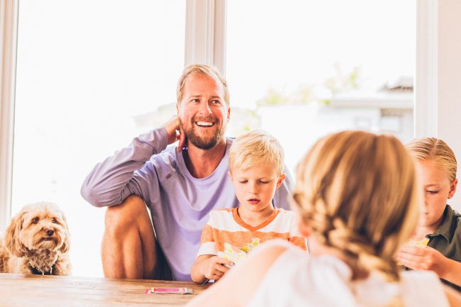 A father and three children plus a dog all sit together on the floor as the children play a game. Thinking about how to discover your life purpose in God.