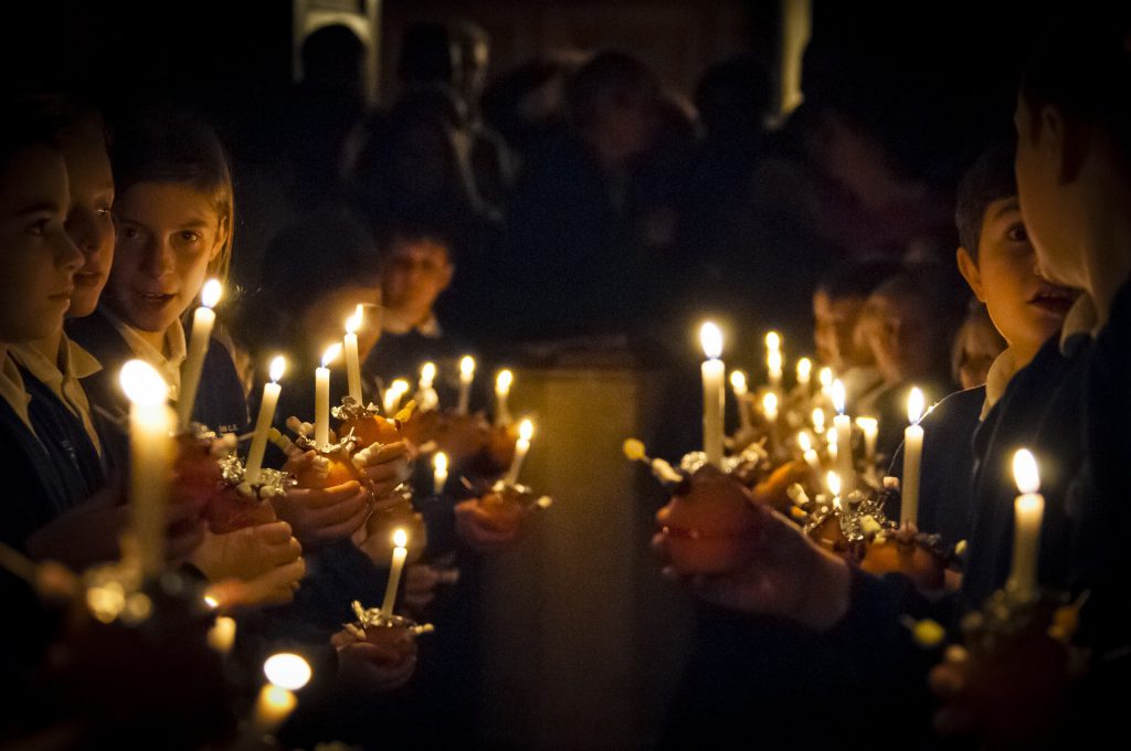 An image of rows of children holdings candles at a Christmas church service.